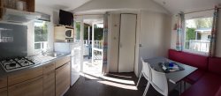 Espace salon/cuisine d’un mobil home pour 2 à 5 personnes équipé de télévision.
