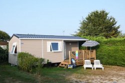 Vue extérieur d’un mobil home pour 4 à 5 personnes avec terrasse semi couverte, barbecue et 2 chaises longues.
