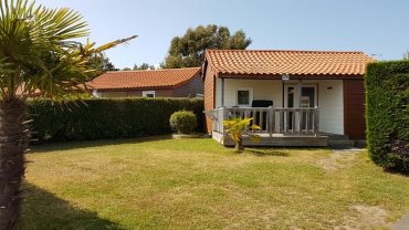 Vue extérieur d’un chalet pour 4 à 6 personnes avec terrasse semi couverte dans camping 4 étoiles.
