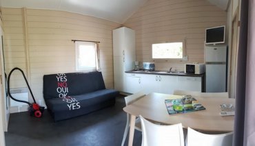 Coin salon/cuisine d’un chalet pour 4 à 6 personnes. Chalet équipé de télévision, lave vaisselle, barbecue dans camping 4 étoiles.
